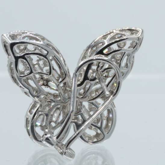 Butterfly-shaped silver earrings on a reflective surface