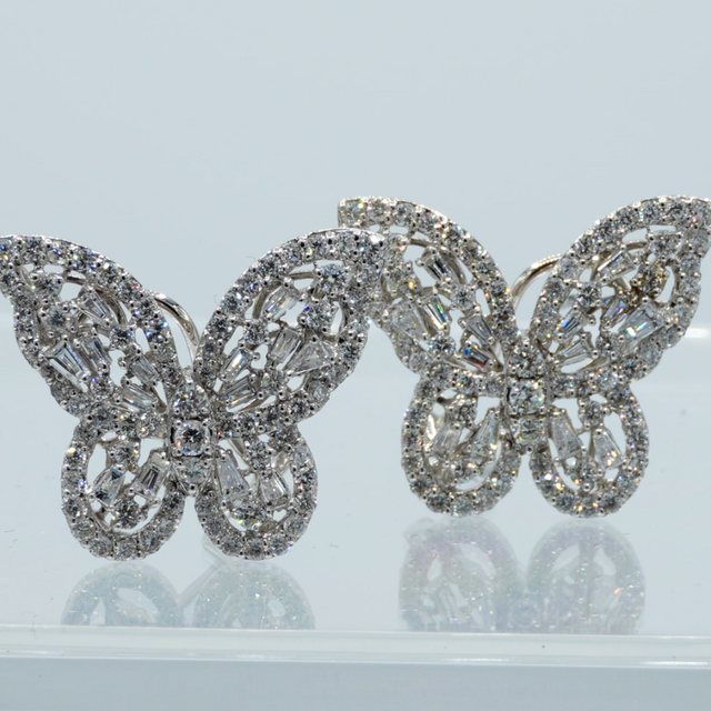 Butterfly-shaped earrings with diamond-like stones on a light gray background